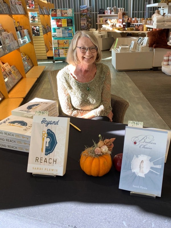 Sandi sitting at her desk with her books on display in Chapters